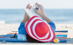 Woman on beach writing memoirs