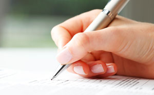Hand holding a pen signing document.