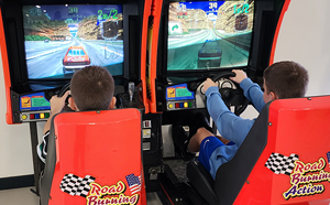 Two children playing an arcade machine.